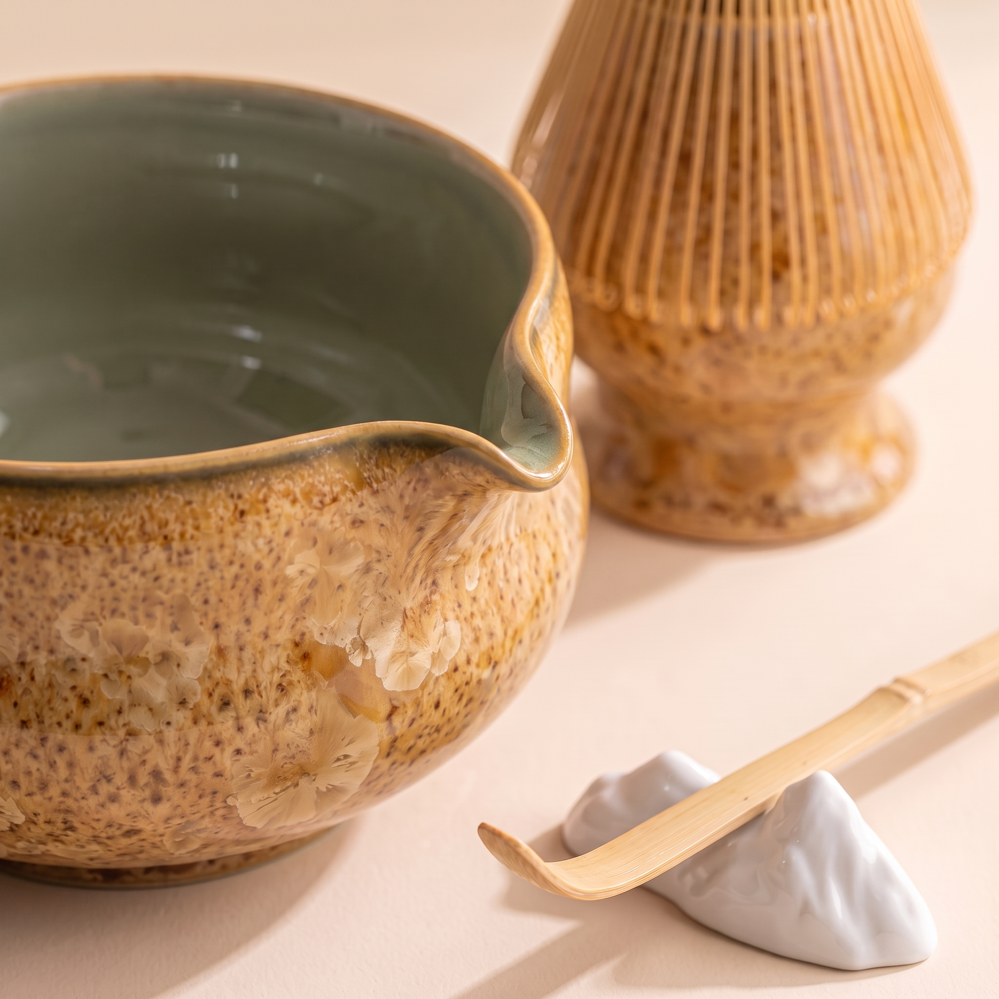 Kumora 7-piece matcha set in Amber — macro close-up of the tan-gold rim, beak spout and crystalline amber glaze