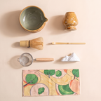 Kumora 7-piece matcha set in Amber — overhead flat-lay of all seven pieces: bowl, holder, whisk, scoop, sifter, rest, mat