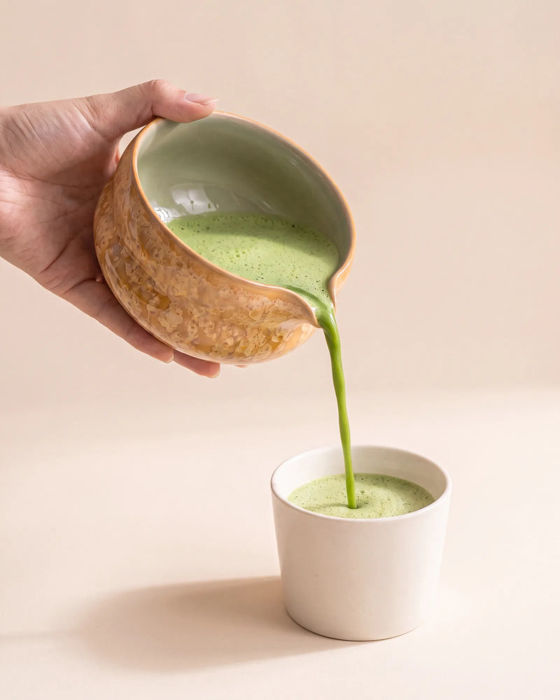 Matcha poured from the spout of the Kumora amber matcha bowl into a cup